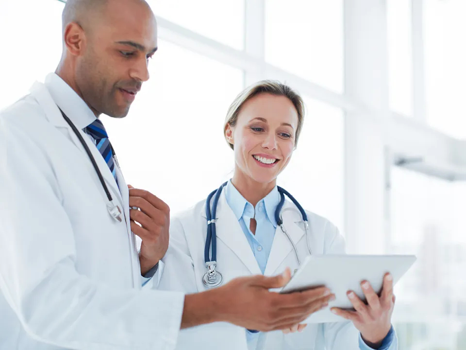 Ein Arzt und eine Ärztin schauen sich gemeinsam Inhalte auf einem Tablet an