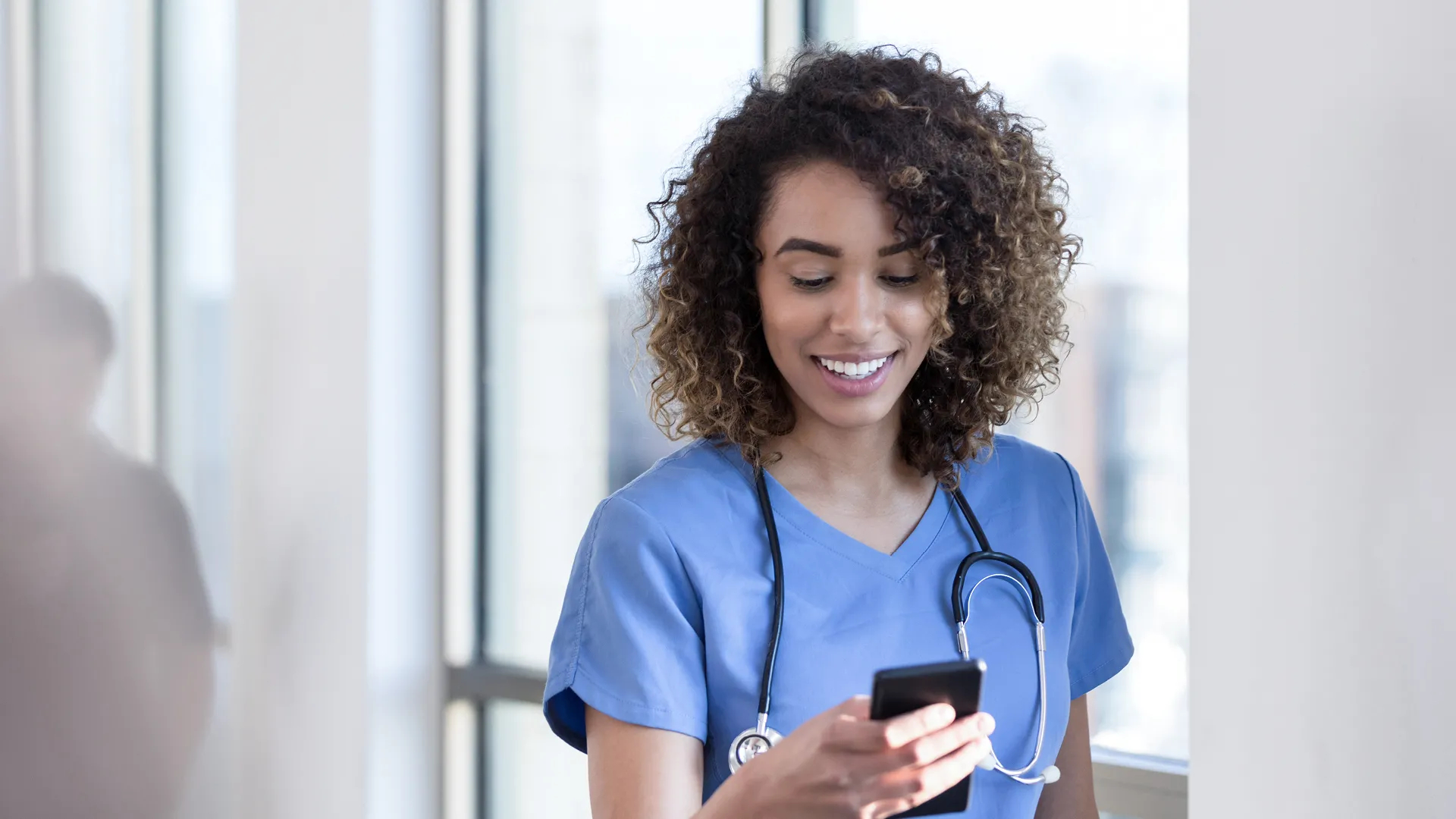 Eine Ärztin bedient lächelnd ihr Handy