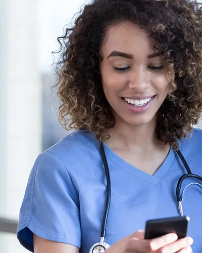 Eine Ärztin bedient lächelnd ihr Handy